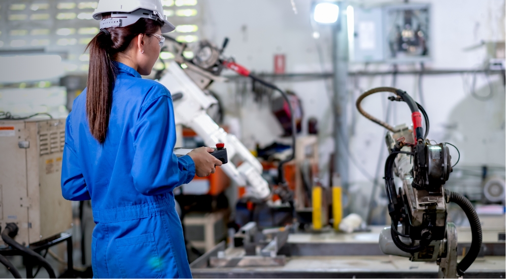 A woman working in a factory with a robot.