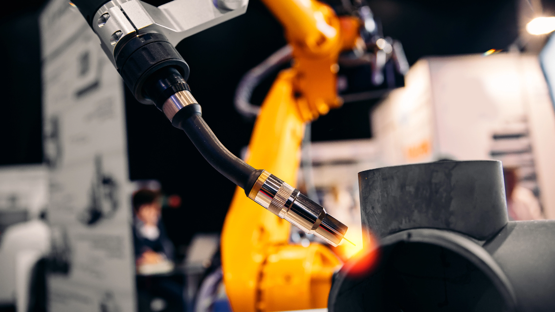 A robot is using a torch to heat up a pipe.