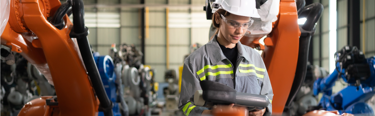 A worker is standing in front of a machine in a factory.