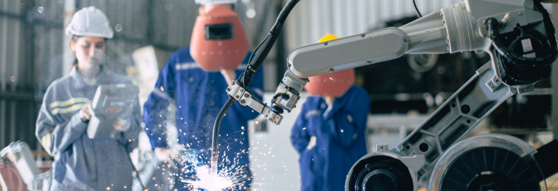 A group of people working with a robot in a factory.