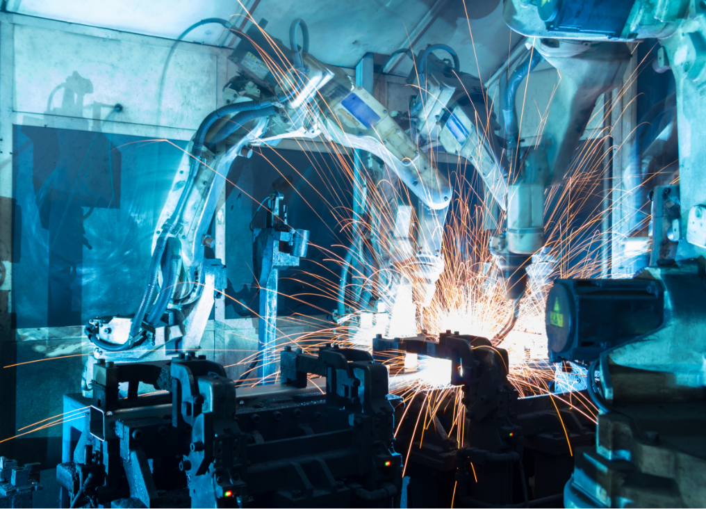 A robot is working in a factory with sparks coming out of it.