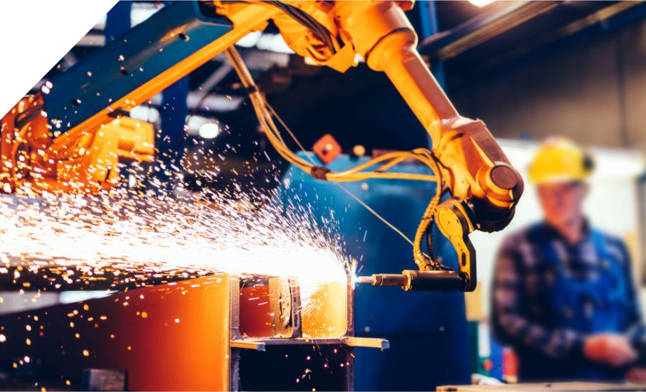 A robot is working in a factory with sparks coming out of it.