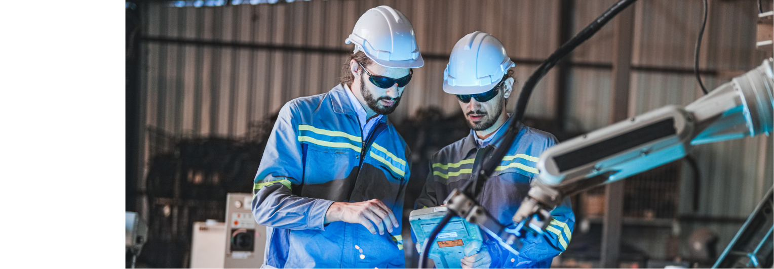 Two workers in hard hats are looking at a machine.